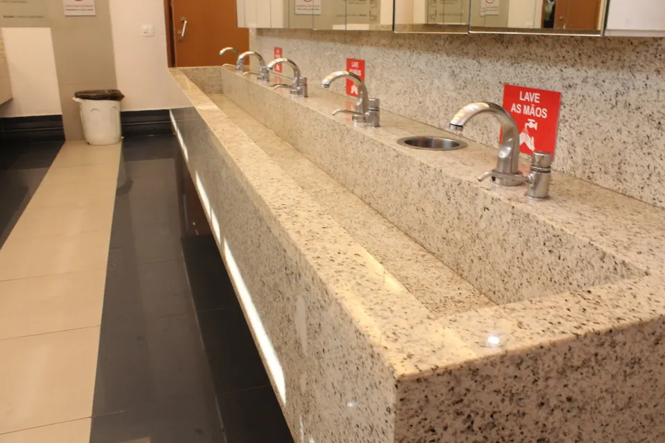 Lavatório coletivo esculpido em granito Branco Polar num banheiro da Galeria Pagé Brás