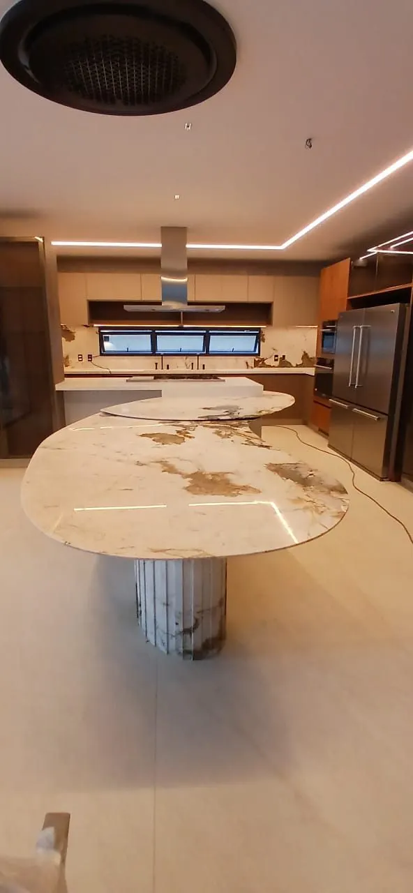 Mesa redonda em mármore branco com veios dourados, instalada em cozinha com pé em quartzito esculpido — Mármore Branco Paraná Calacatta Gold