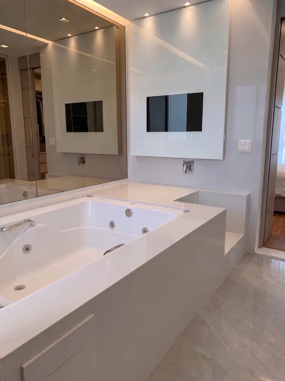 Banheira de hidromassagem revestida em branco prime, com saia em peça única, tampo de apoio e banco lateral no mesmo material