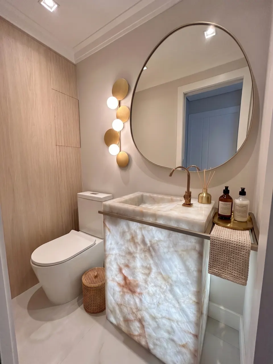 Lavatório de lavabo em quartzito ônix cristallo iluminado por trás, com cuba esculpida na própria pedra e painel frontal em peça única