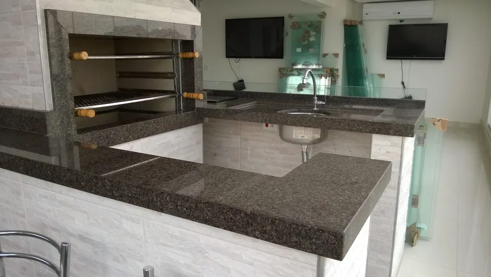 Churrasqueira em granito marrom café com acabamento granulado, integrada a bancada da cozinha com área de preparo — Granito Café Imperial