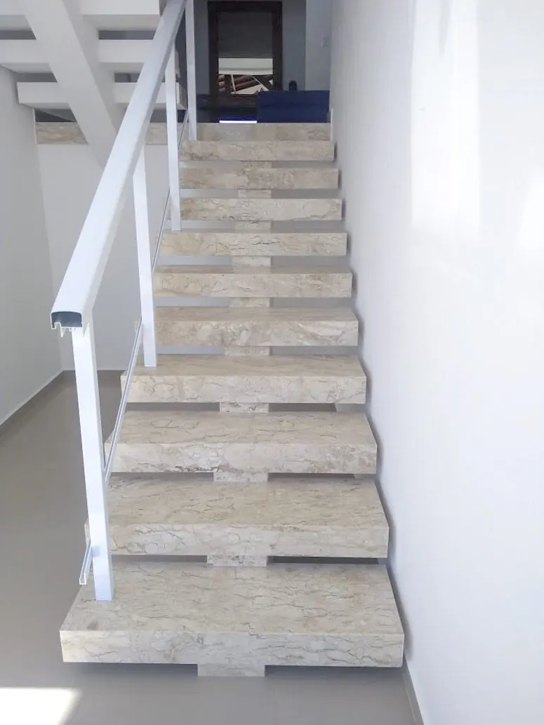 Escada interna em mármore travertino nacional com degraus largos e acabamento uniforme
